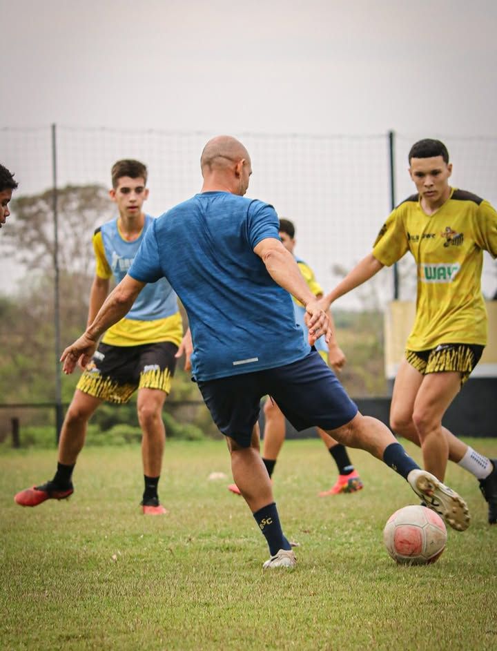 Professor da Basílio Sport Center ao lado de um aluno, com bolas, cones e squeezes personalizados da escola